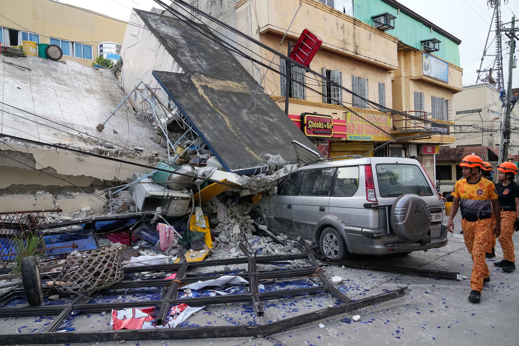 Firemen walk beside a collapsed building caused by a recent strong earthquake in Bogo city, Cebu Province, Central Philippines on Thursday, Oct. 2, 2025. (AP Photo/Aaron Favila)