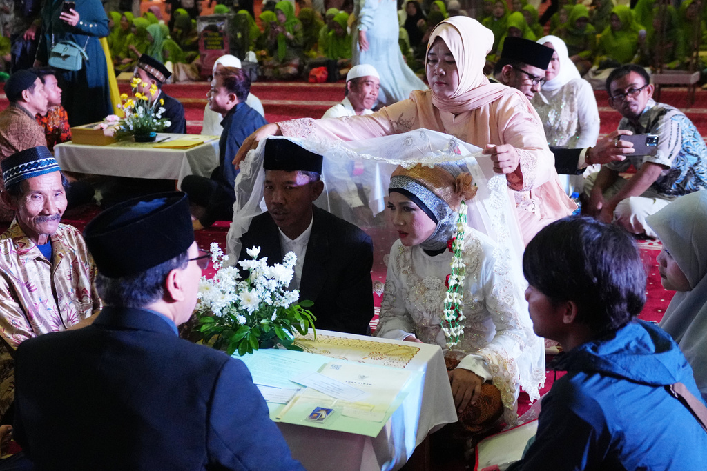 Fauzi, left, who uses only one name, and his bride Endah Kartini take part in a mass wedding ceremony at Istiqlal Mosque in Jakarta, Indonesia, Wednesday, Dec. 3, 2025. (AP Photo/Tatan Syuflana)
