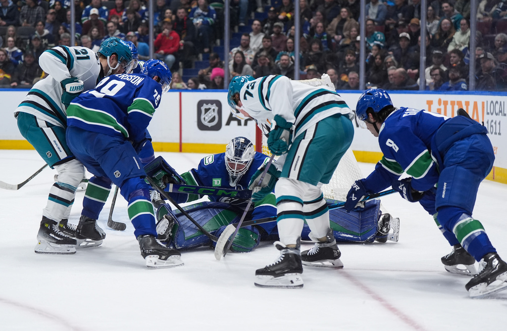 Vancouver Canucks goalie Nikita Tolopilo, center, stops San Jose Sharks' Tyler Toffoli (73) and Alex Wennberg (21) as Vancouver's Marcus Pettersson (29) and Conor Garland (8) defend during the first period of an NHL hockey game, in Vancouver, on Tuesday, Jan. 27, 2026. (Darryl Dyck/The Canadian Press via AP)