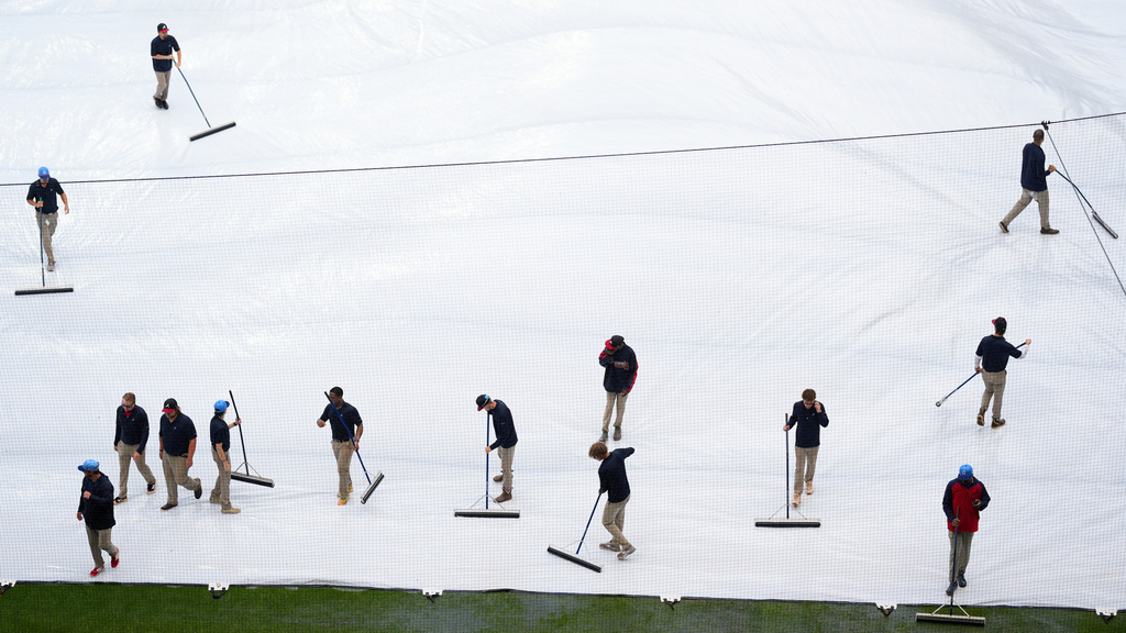 Grounds crew removes water from the tarp in a rain-delayed second inning of a baseball game between the Atlanta Braves and the Washington Nationals, Saturday, May 23, 2026, in Atlanta. (AP Photo/Mike Stewart)