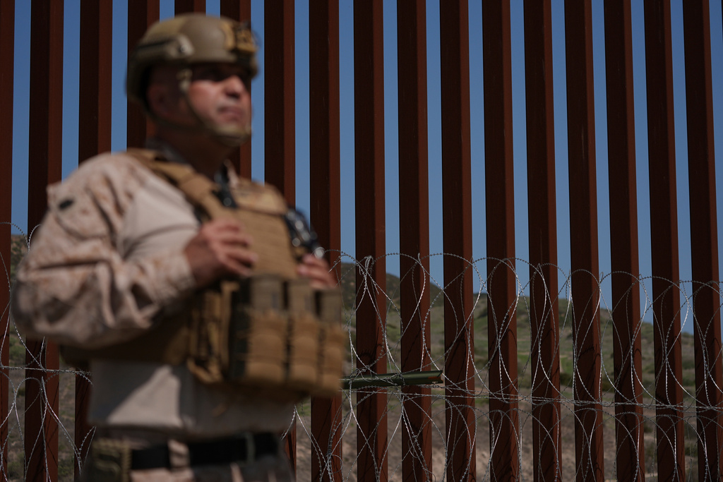 FILE - A Marine stands front of newly-installed concertina wire lining one of two border walls separating Mexico from the United States during a news conference, March 21, 2025, in San Diego. (AP Photo/Gregory Bull, File)