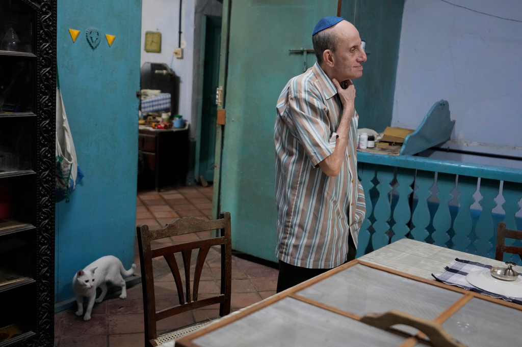 Keith Hallegua, a Paradesi Jew, stands next to his dining table as his cat walks past at his home in the historic Jew Town neighborhood of Kochi, India, Thursday, May 21, 2026. (AP Photo/Aijaz Rahi)