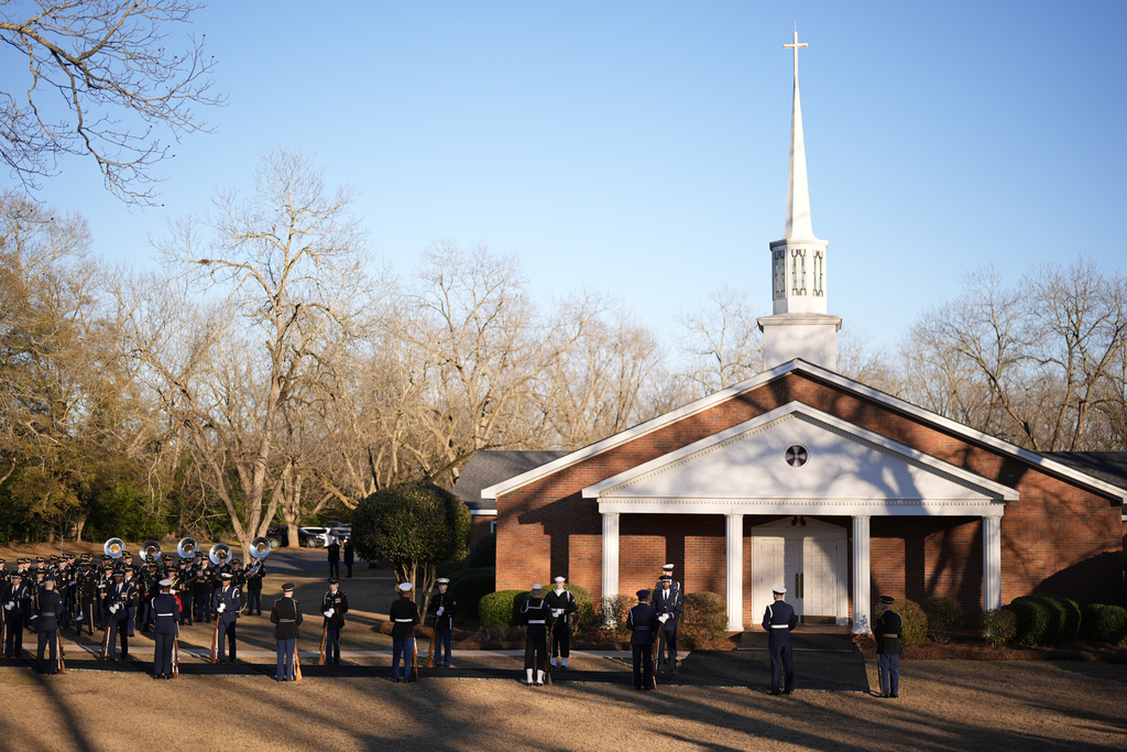 An honor guard and honor guard band march before the casket of former President Jimmy Carter arrives at Maranatha Baptist Church for a funeral service, Thursday, Jan. 9, 2025, in Plains, Ga. (AP Photo/Mike Stewart)
