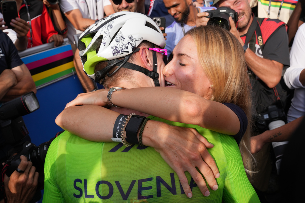 Slovenia's Tadej Pogacar celebrates with his partner Urska Zigart after winning the men's Elite road race, at the road cycling World Championships in Kigali, Rwanda, Sunday, Sept. 28, 2025. (AP Photo/Jerome Delay)
