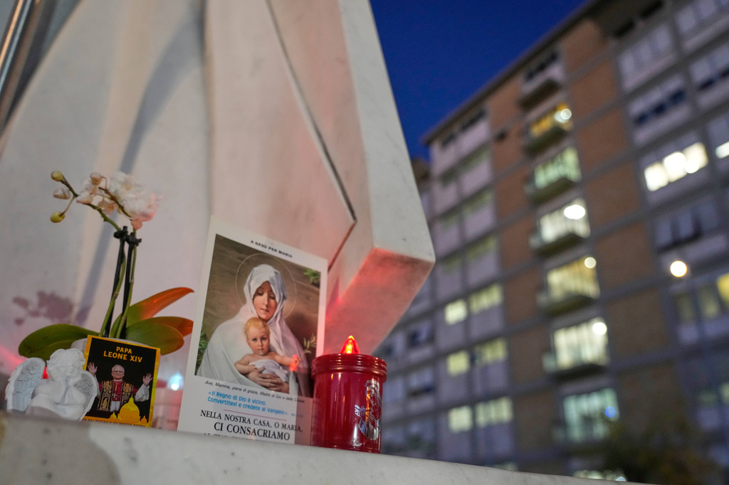 An image of Pope Leo XIV rests at the base of a statue of late pope St. John Paul II outside the Agostino Gemelli Polyclinic, where Leo is hospitalized for surgery to remove a lung nodule, in Rome, Tuesday, Oct. 13, 2026. (AP Photo/Gregorio Borgia)
