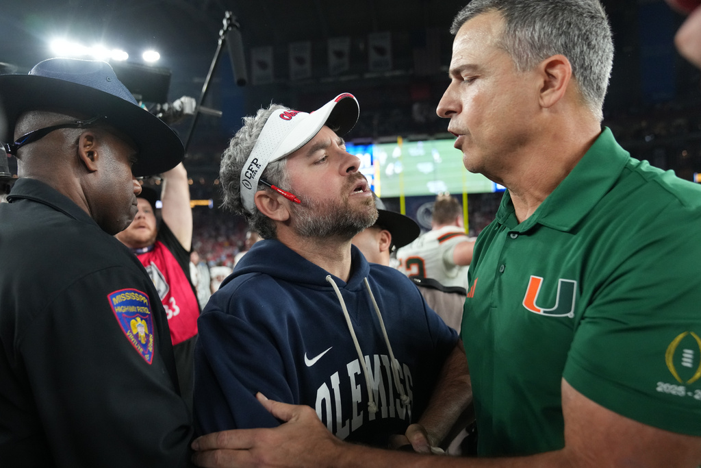 CORRECTS TO MISSISSIPPI HEAD COACH PETE GOLDING NOT MISSISSIPPI HEAD COACH MARIO CRISTOBAL - Mississippi head coach Pete Golding, center, greets Miami head coach Mario Cristobal, right, after the Fiesta Bowl NCAA college football playoff semifinal game, Thursday, Jan. 8, 2026, in Glendale, Ariz. (AP Photo/Rick Scuteri)