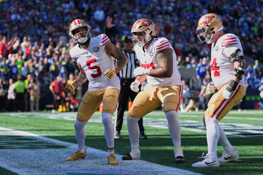 San Francisco 49ers wide receiver Mike Evans (5) celebrates his touchdown catch with offensive tackle Dominick Puni (77), and enter Jake Brendel (64) during the first half of an NFL football game against the Seattle Seahawks, Sunday, Oct. 11, 2026, in Seattle. (AP Photo/Lindsey Wasson)