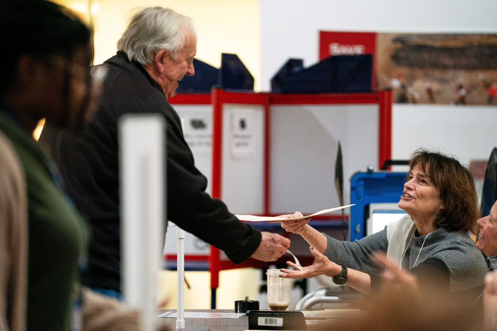 An election worker hands a voter his ballot at Alexandria City Hall, Tuesday, Nov. 4, 2025, in Alexandria, Va. (AP Photo/Allison Robbert)