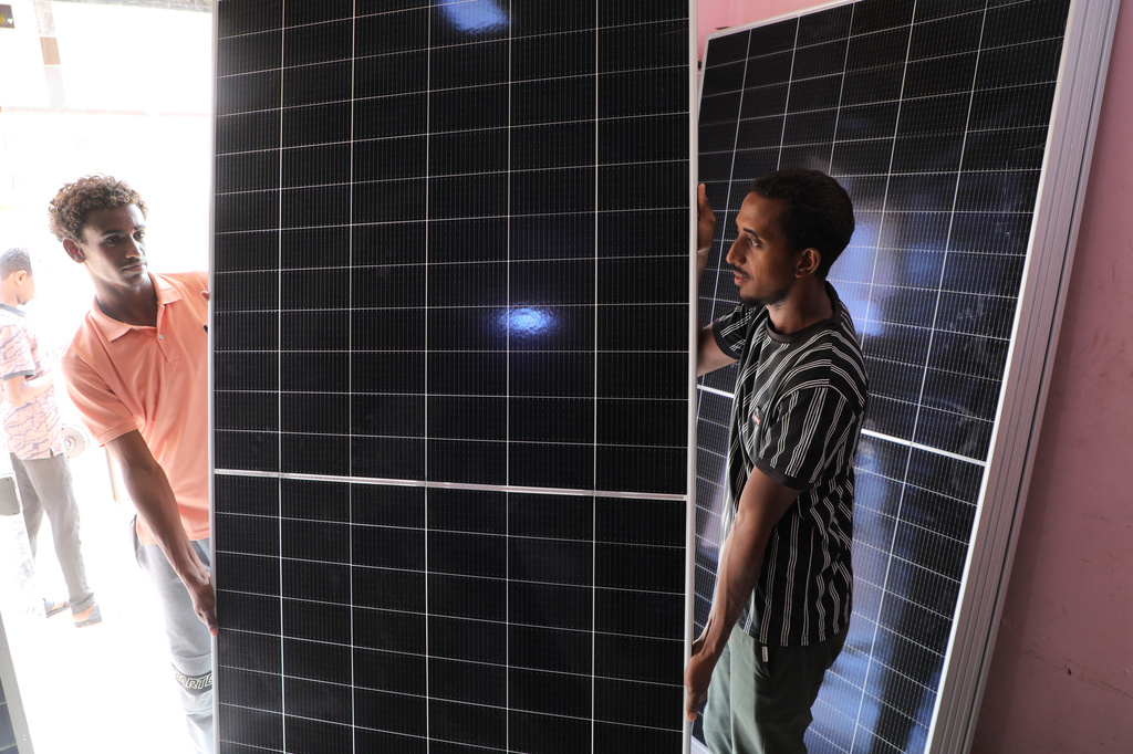 Workers carry a panel ready for installation at a solar energy systems store in Omdurman, on the outskirts of Khartoum, Sudan, July 23, 2026. (AP Photo/Mohnd Blal)