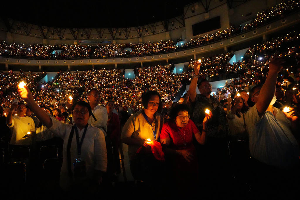 People hold electric candles as they sing during a Christmas Eve service at Indonesia Arena stadium in Jakarta, Indonesia, Wednesday, Dec. 24, 2025. (AP Photo/Tatan Syuflana)