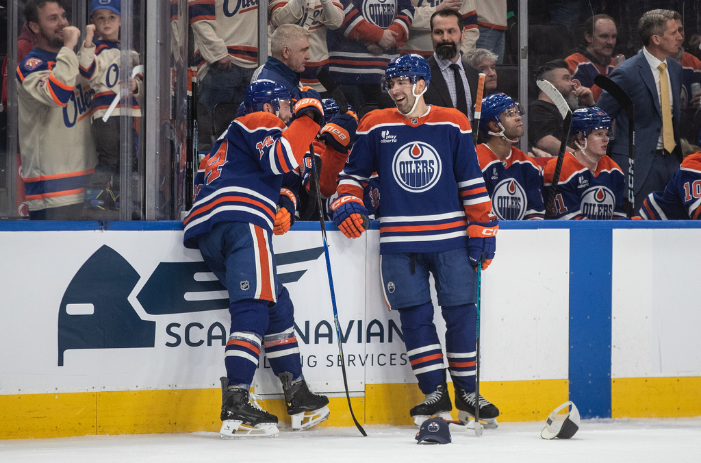 Edmonton Oilers' Mattias Ekholm (14) and Evan Bouchard, right, laugh after Ekholm scored a hat trick during third-period NHL hockey game action against the Anaheim Ducks in Edmonton, Alberta, Monday, Jan. 26, 2026. (Jason Franson/The Canadian Press via AP)