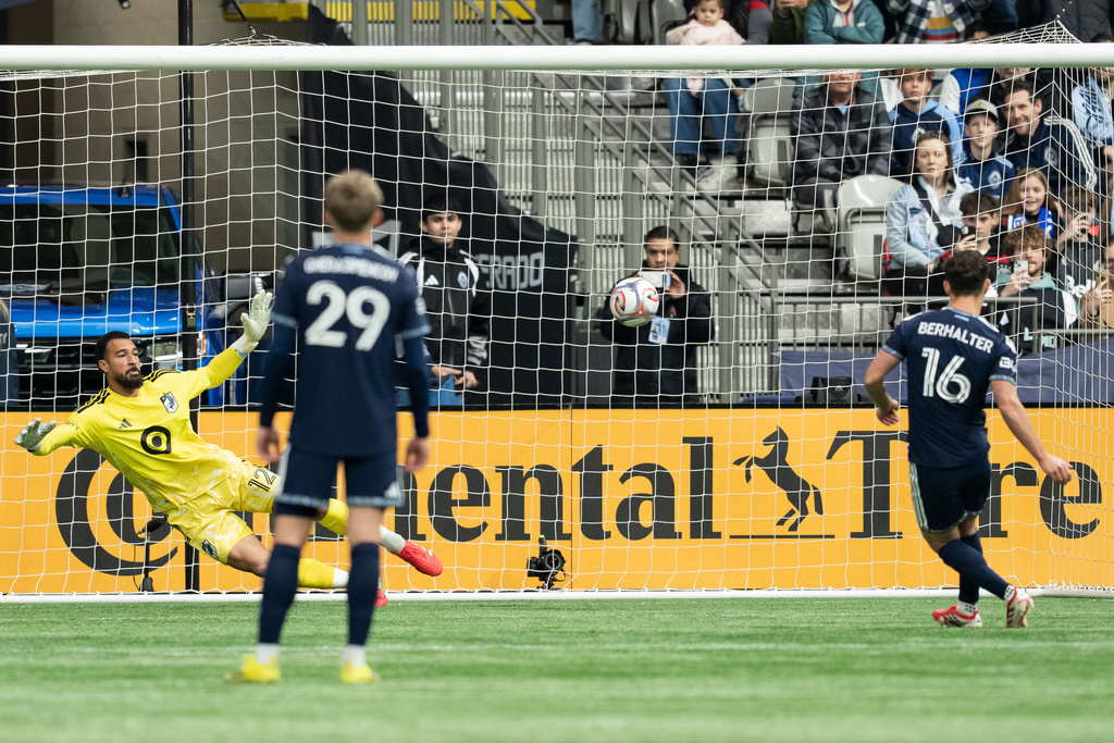 Vancouver Whitecaps' Sebastian Berhalter (16) scores on Minnesota United goalkeeper Drake Callender as Vancouver's Mihail Gherasimencov (29) watches during the first half of an MLS soccer match in Vancouver, British Columbia, Sunday, March 15, 2026. (Ethan Cairns/The Canadian Press via AP)
