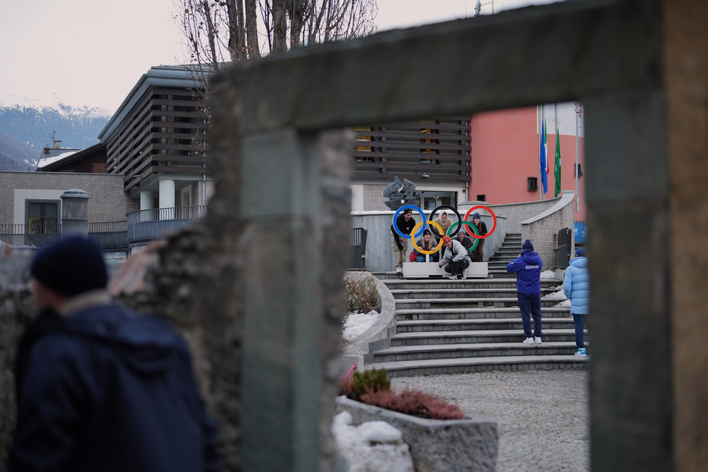 People pose for pictures next to Olympic rings in Bormio, Italy, during the 2026 Winter Olympics, Tuesday, Feb. 10, 2026. (AP Photo/Rebecca Blackwell)