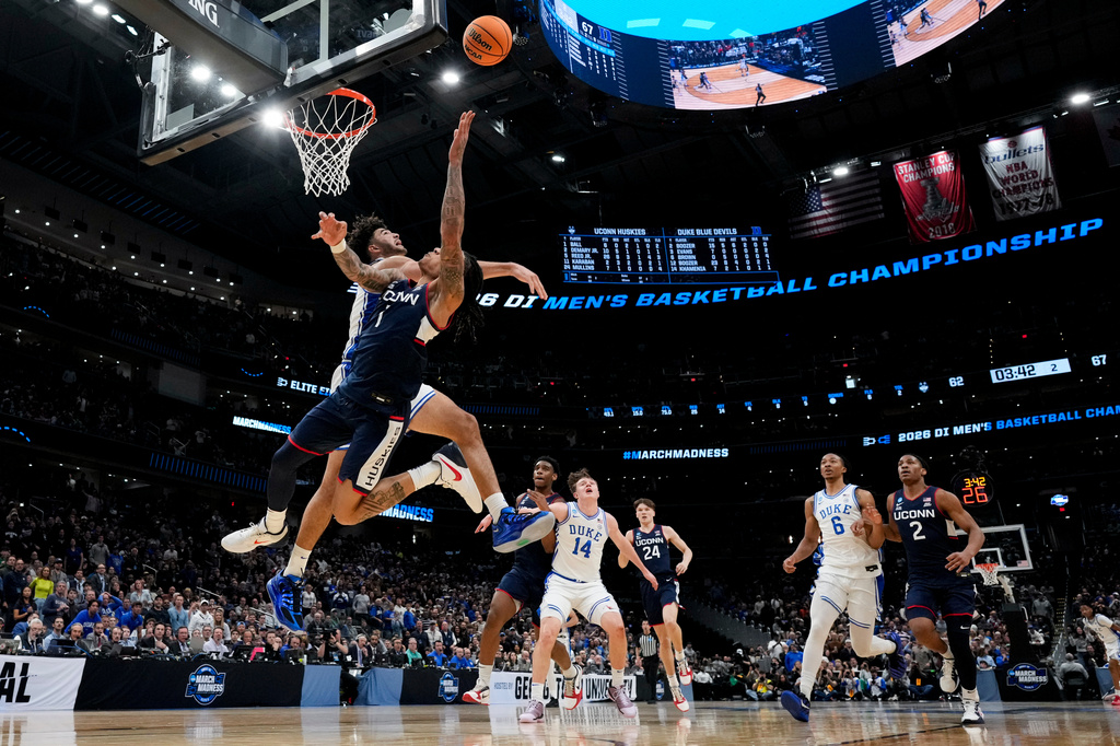 UConn guard Solo Ball scores over Duke guard Cayden Boozer, rear, during the second half in the Elite Eight of the NCAA college basketball tournament, Sunday, March 29, 2026, in Washington. (AP Photo/Stephanie Scarbrough)