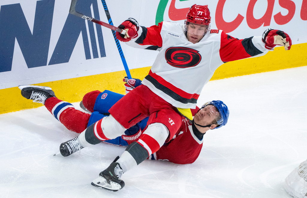 Montreal Canadiens' Mike Matheson (8) gets tangled up with Carolina Hurricanes' Taylor Hall (71) during the second period of an NHL hockey game in Montreal on Tuesday, March 24, 2026. (Christinne Muschi/The Canadian Press via AP)