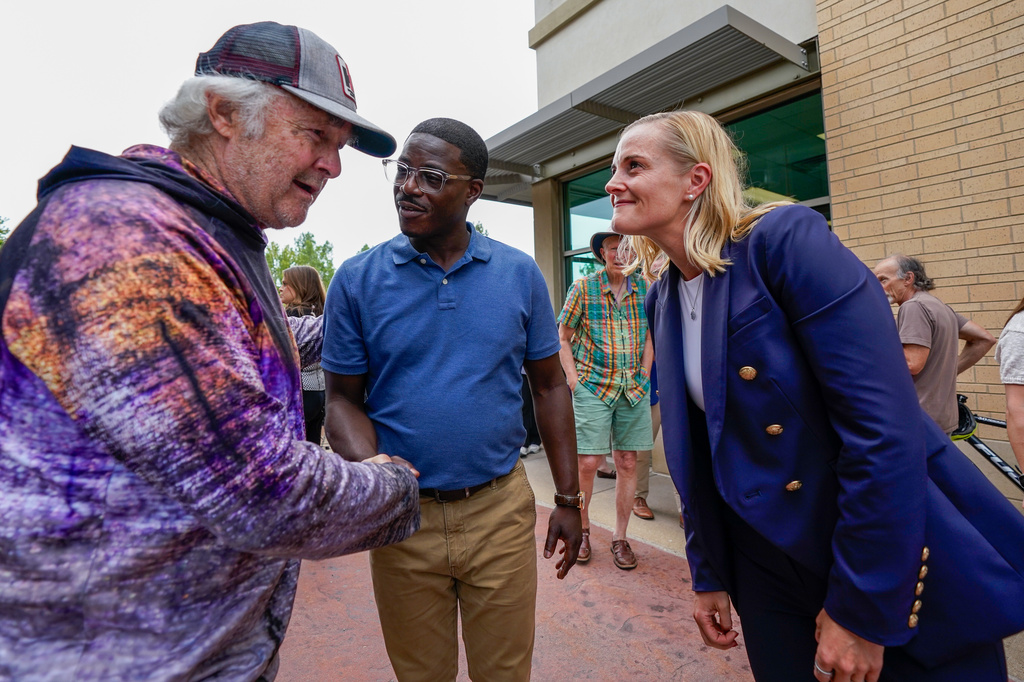 Democratic gubernatorial nominee David Crowley, center, and lieutenant governor nominee Sarah Godlewski, right, meet supporter Mike Balisle, left, following a breakfast with Democratic leaders Wednesday, Aug. 12, 2026, in Middleton, Wis. (AP Photo/Kayla Wolf)