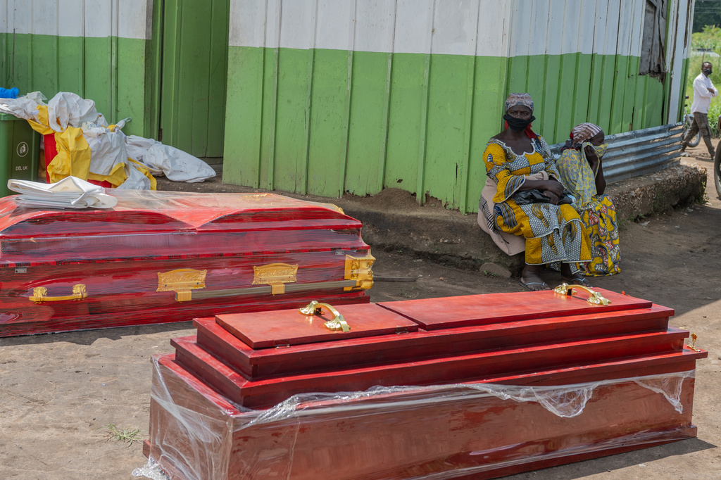 Two women sit beside coffins at a health center in Rwampara, Congo, Wednesday, May 20, 2026. (AP Photo/Moses Sawasawa)