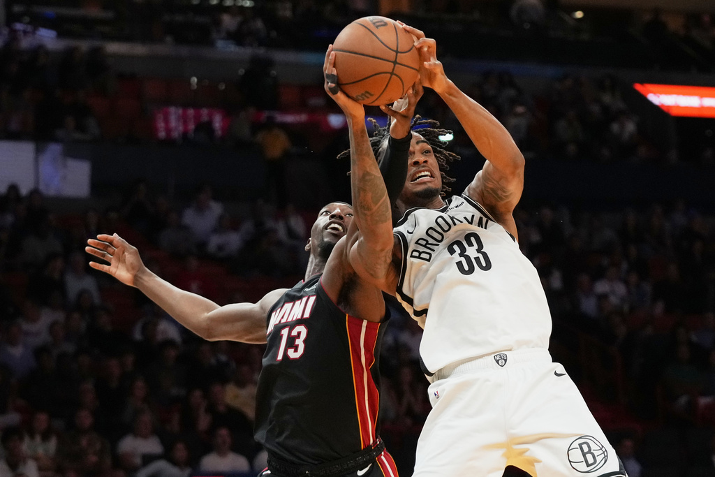 Miami Heat center Bam Adebayo (13) and Brooklyn Nets center Nic Claxton (33) compete for the ball during the second half of an NBA basketball game, Tuesday, March 3, 2026, in Miami. (AP Photo/Lynne Sladky)
