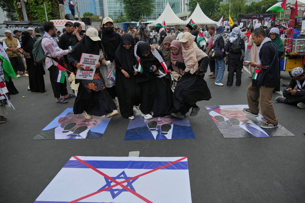 Protesters stomp on portraits of, from left, Israel's Prime Minister Benjamin Netanyahu, Israel's National Security Minister Itamar Ben-Gvir, and US President Donald Trump, during a rally commemorating the second anniversary of the war in Gaza, outside the US Embassy in Jakarta, Indonesia, Tuesday, Oct. 7, 2025. (AP Photo/Achmad Ibrahim)