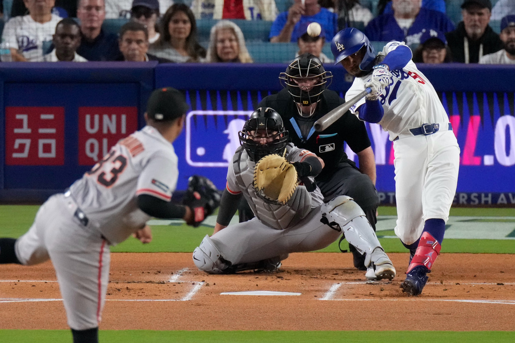 Los Angeles Dodgers' Mookie Betts, right, hits a solo home run as San Francisco Giants pitcher Cesar Perdomo, left, and catcher Drew Cavanaugh watch during the first inning of a baseball game Friday, Sept. 18, 2026, in Los Angeles. (AP Photo/Mark J. Terrill)