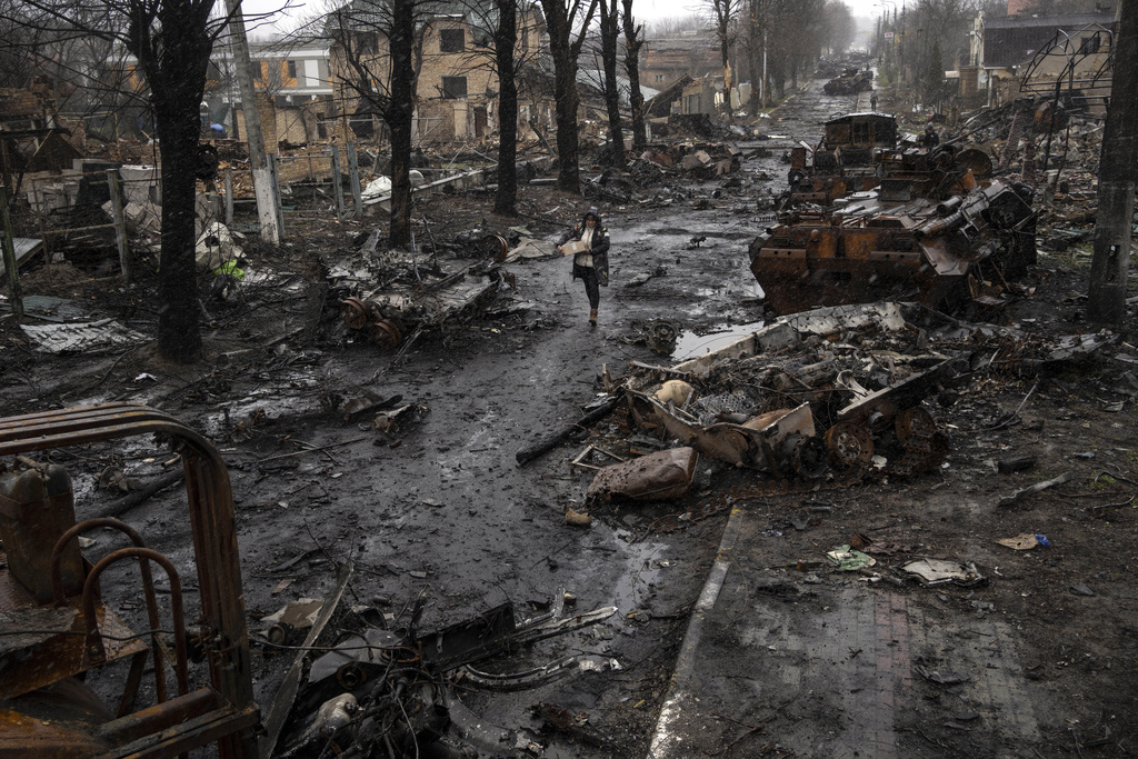 FILE - A woman walks amid destroyed Russian tanks in Bucha, on the outskirts of Kyiv, Ukraine, April 3, 2022. (AP Photo/Rodrigo Abd, File)