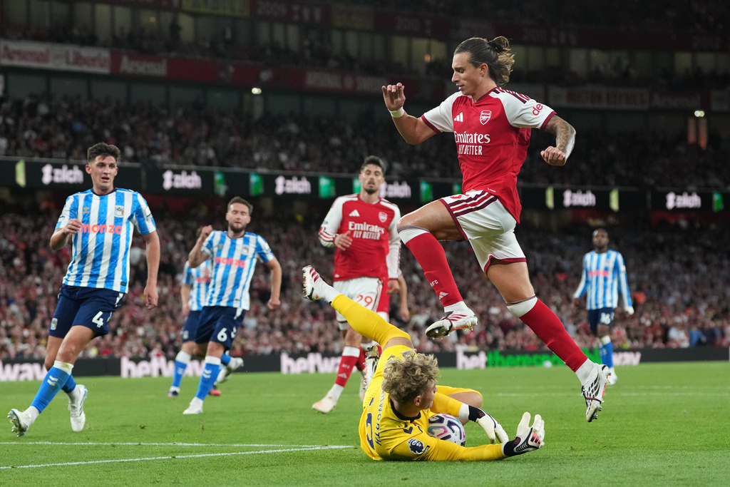 Arsenal's Riccardo Calafiori leaps over Coventry City's goalkeeper Carl Rushworth during the English Premier League soccer match between Arsenal and Coventry City in London, Friday, Aug. 21, 2026. (AP Photo/Kirsty Wigglesworth)