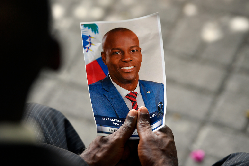 FILE - A person holds a photo of late Haitian President Jovenel Moise during his memorial ceremony at the National Pantheon Museum in Port-au-Prince, Haiti, July 20, 2021. (AP Photo/Matias Delacroix, File)