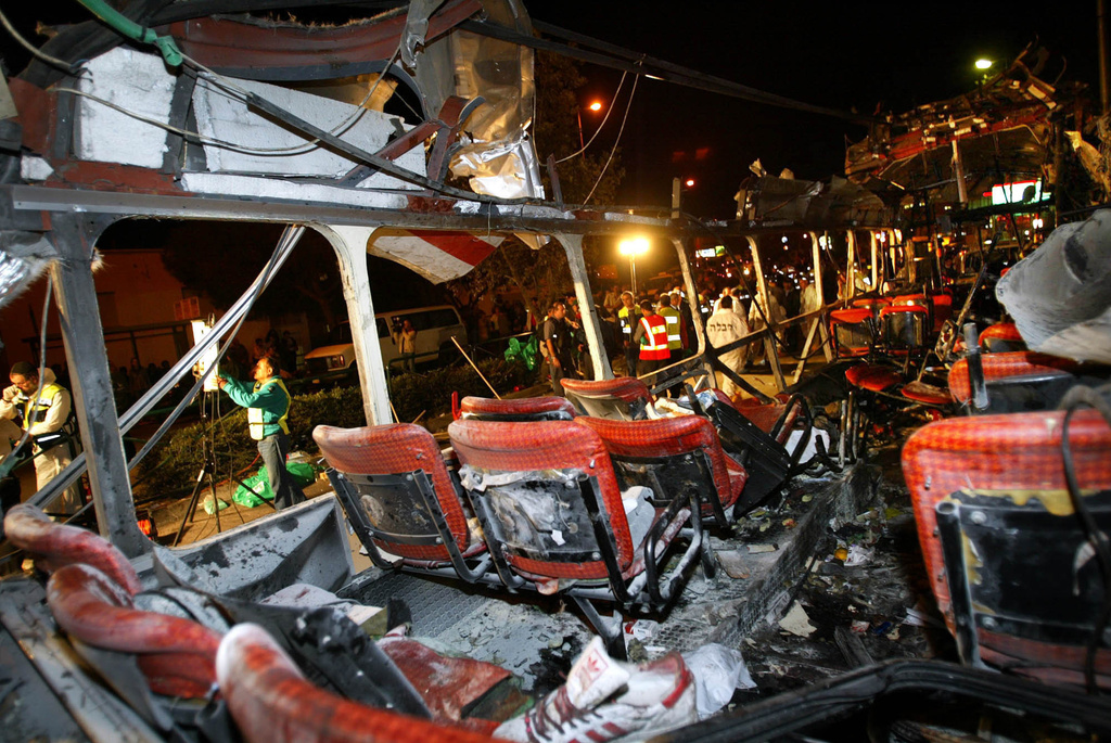 FILE - Police forensic officers work amid the remains of a bombed bus in the northern Israeli city of Haifa Wednesday, March 5, 2003. (AP Photo/Brennan Linsley, File)