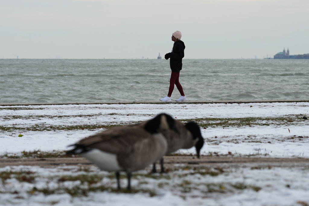 A woman bundles up as she takes a walk in the snow-covered at Lake Michigan during a cold day in Chicago, Tuesday, Nov. 11, 2025. (AP Photo/Nam Y. Huh)