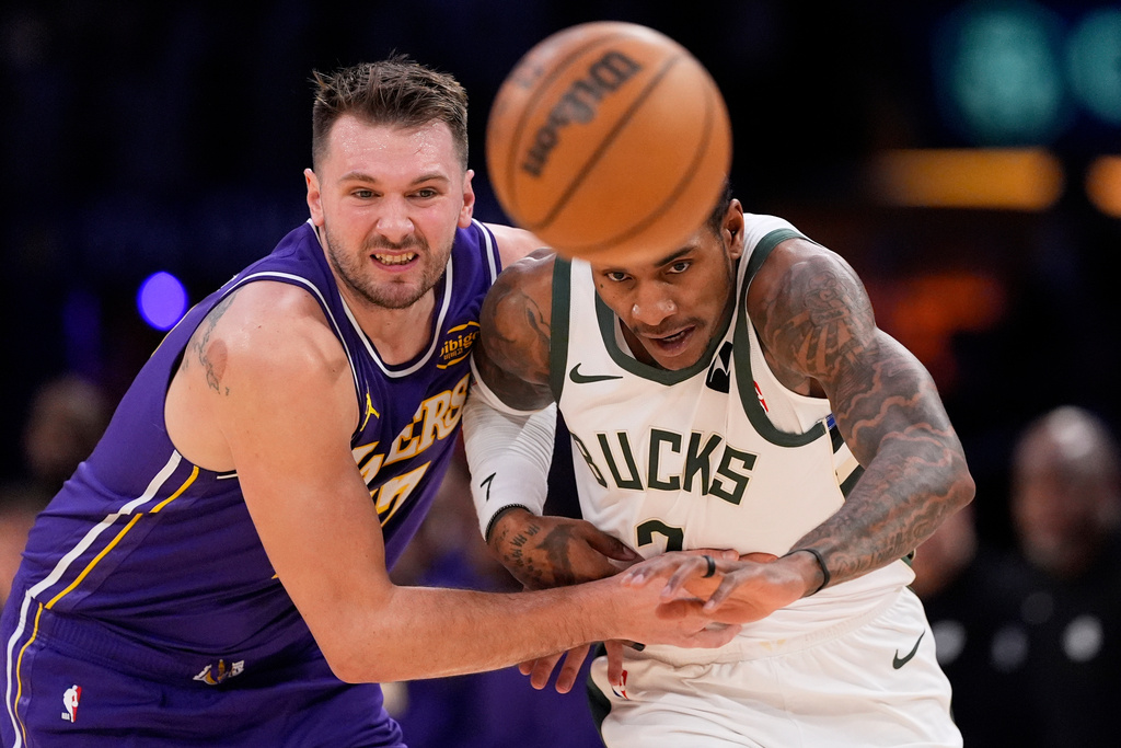 Los Angeles Lakers guard Luka Doncic, left, and Milwaukee Bucks guard Kevin Porter Jr. go after a loose ball during the first half of an NBA basketball game Friday, Jan. 9, 2026, in Los Angeles. (AP Photo/Mark J. Terrill)
