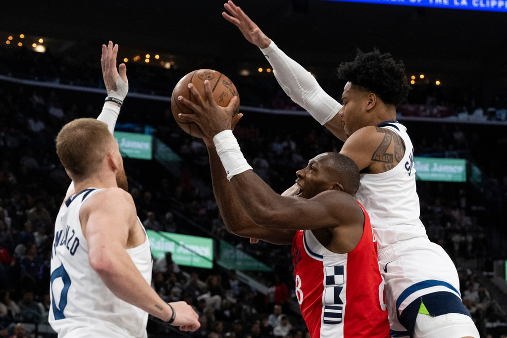 Los Angeles Clippers guard Kris Dunn, center, goes up for a basket as Minnesota Timberwolves guards Terrence Shannon Jr., right, and Donte DiVincenzo, left, defend against him during the first half of an NBA basketball game Thursday, Feb. 26, 2026, in Inglewood, Calif. (AP Photo/Kyusung Gong)
