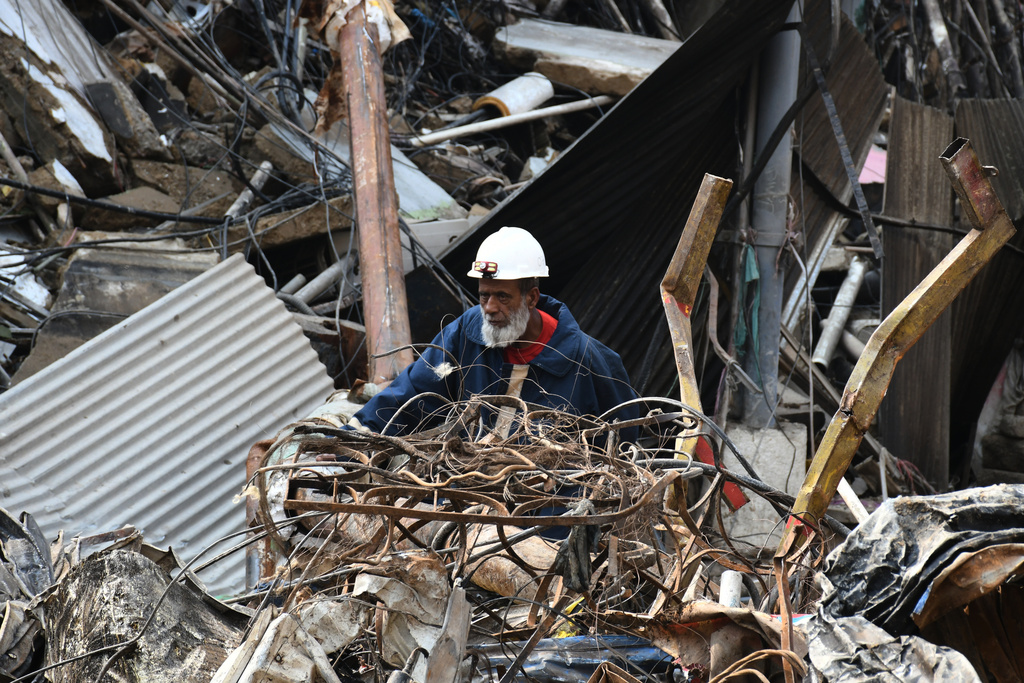 A firefighter searches through the rubble of a burnt building of a multistory shopping plaza following a massive fire in Karachi, Pakistan, Monday, Jan. 19, 2026. (AP Photo/Ali Raza)