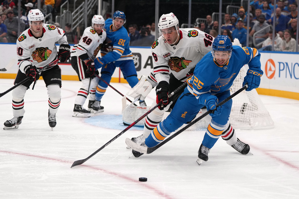 St. Louis Blues' Jordan Kyrou (25) and Chicago Blackhawks' Louis Crevier (46) battle for a loose puck during the second period of an NHL hockey game Wednesday, Oct. 15, 2025, in St. Louis. (AP Photo/Jeff Roberson)