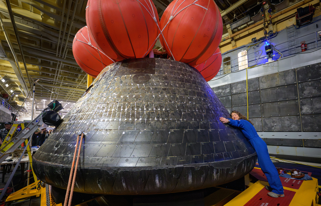 In this photo provided by NASA, Artemis II mission specialist and NASA astronaut Christina Koch hugs the Orion spacecraft aboard the USS John P. Murtha, Saturday, April 11, 2026, off the coast of California. (Bill Ingalls/NASA via AP)