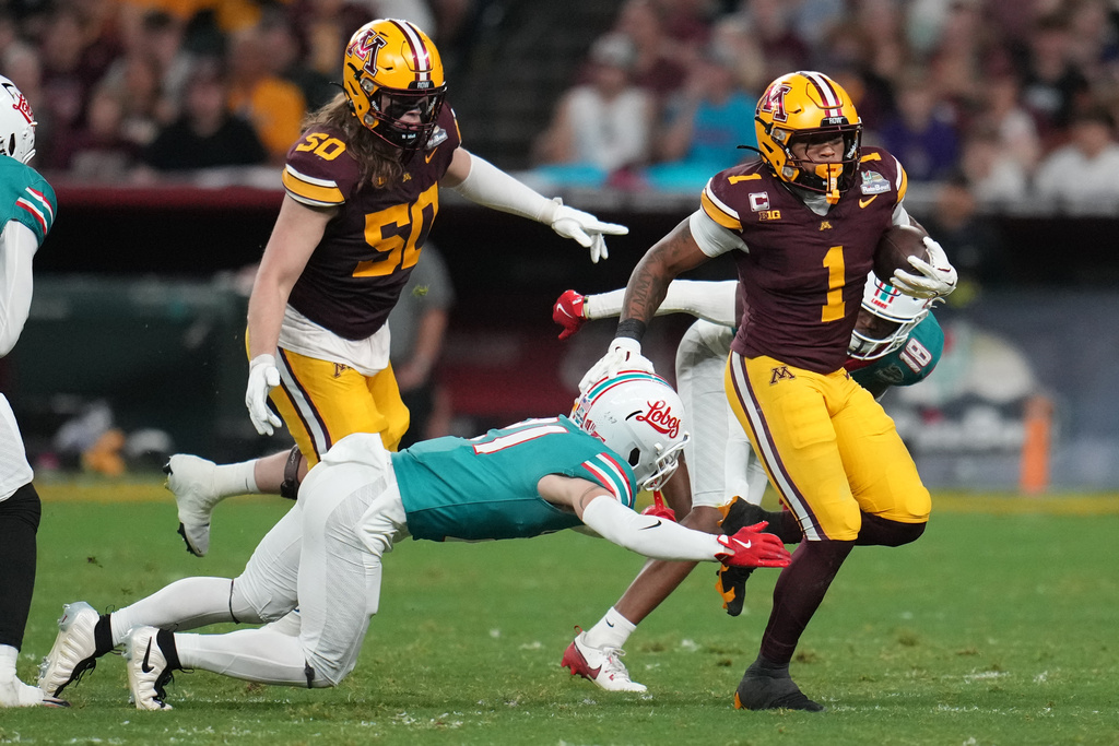 Minnesota running back Darius Taylor (1) runs around New Mexico safety Austin Brawley in the first half of a Rate Bowl NCAA college football game, Friday, Dec. 26, 2025, in Phoenix. (AP Photo/Rick Scuteri)
