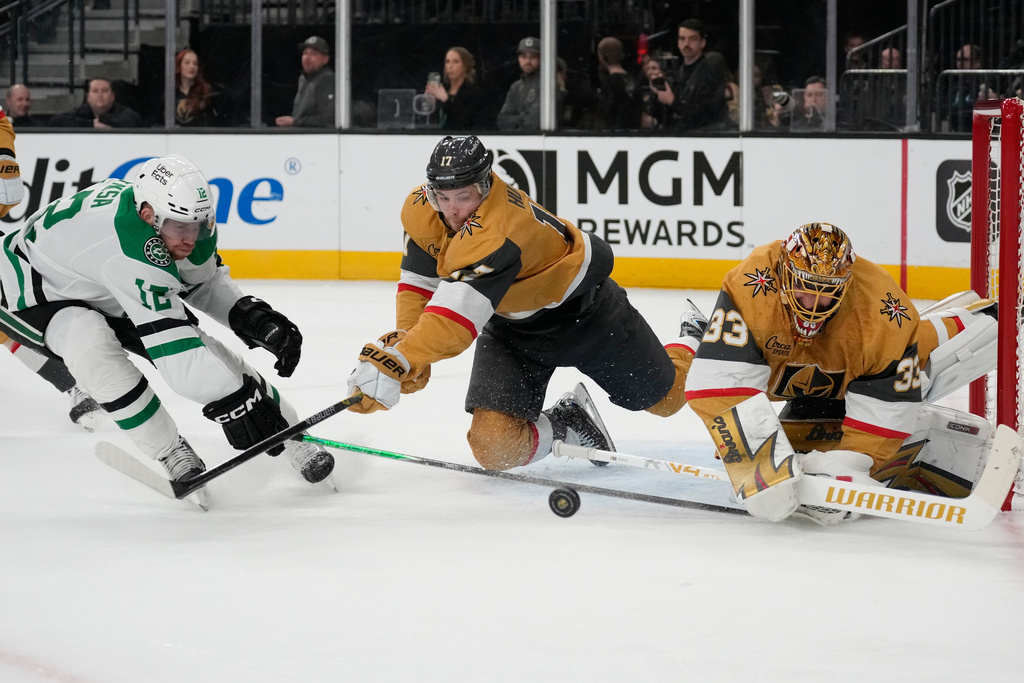Vegas Golden Knights defenseman Ben Hutton (17) and Vegas Golden Knights goaltender Adin Hill (33) try to knock the puck away from Dallas Stars center Radek Faksa (12) during the first period of an NHL hockey game Thursday, Jan. 29, 2026, in Las Vegas. (AP Photo/John Locher)