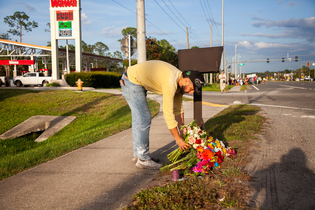 Edgar Olalde, of Jacksonville, who knew the victim from his store, lays a bouquet of flowers during a vigil for a Mexican man who was struck and killed by a tractor trailer while running from an encounter with Immigration and Customs Enforcements officers the day before, Wednesday, July 15, 2026, in St. Augustine, Fla. (AP Photo/Kelly Jordan)