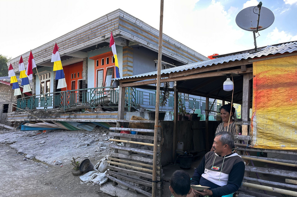 People sit near a house collapsed during an earthquake in North Lamba Leda, East Nusa Tenggara province, Indonesia, Wednesday, Aug. 19, 2026. (AP Photo/Firdia Lisnawati)