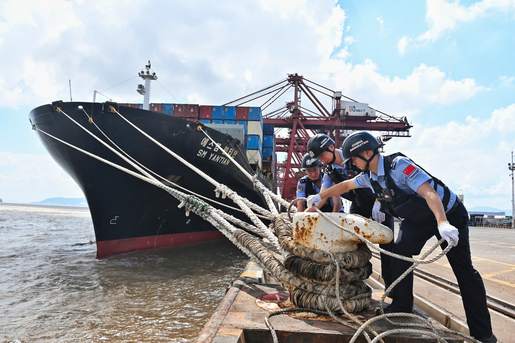 In this photo released by Xinhua News Agency, police officers check the mooring lines of a vessel ahead of Typhoon Dolphin in Beilun District of Ningbo City, east China's Zhejiang Province, on Aug. 7, 2026.(Hu Jiajie/Xinhua via AP)
