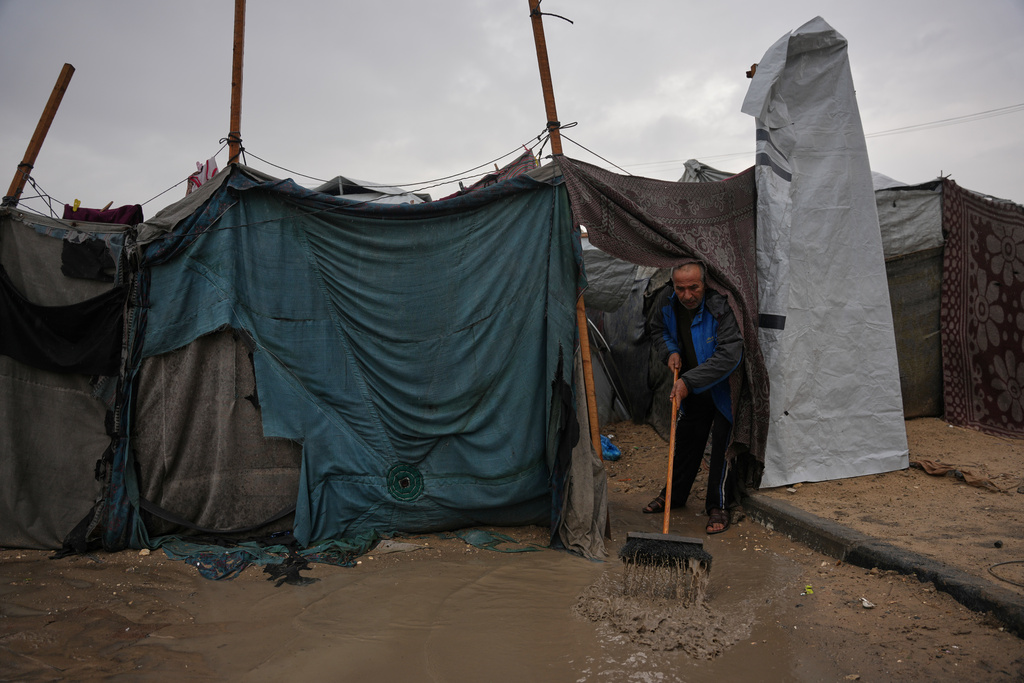 Hosni Abu Reda clears water from his tent at a camp for displaced Palestinians following heavy rain in Khan Younis, southern Gaza Strip, Thursday, Dec. 11, 2025. (AP Photo/Abdel Kareem Hana)