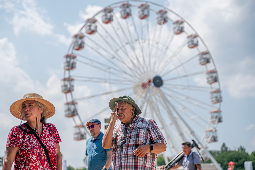 Visitors react to the heat while attending the Great American State Fair on the National Mall, Wednesday, July 1, 2026, in Washington. (AP Photo/Nathan Howard)
