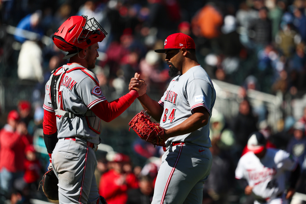 Cincinnati Reds catcher Tyler Stephenson (37) and pitcher Tony Santillan (64) celebrate after winning a baseball game against the Minnesota Twins, Saturday, April 18, 2026, in Minneapolis. (AP Photo/Ellen Schmidt)