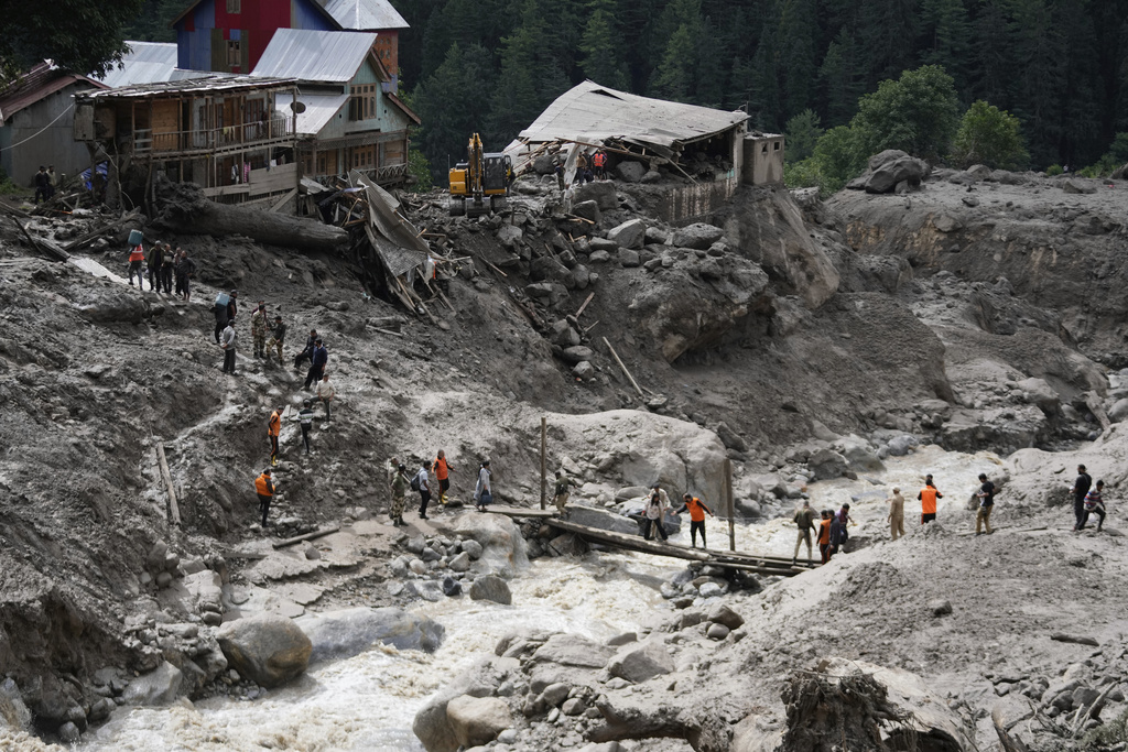 Stranded pilgrims are helped across a water channel using a makeshift bridge a day after flash floods in Chositi village, Kishtwar district, Indian-controlled Kashmir, Friday, Aug. 15, 2025. (AP Photo/Channi Anand)