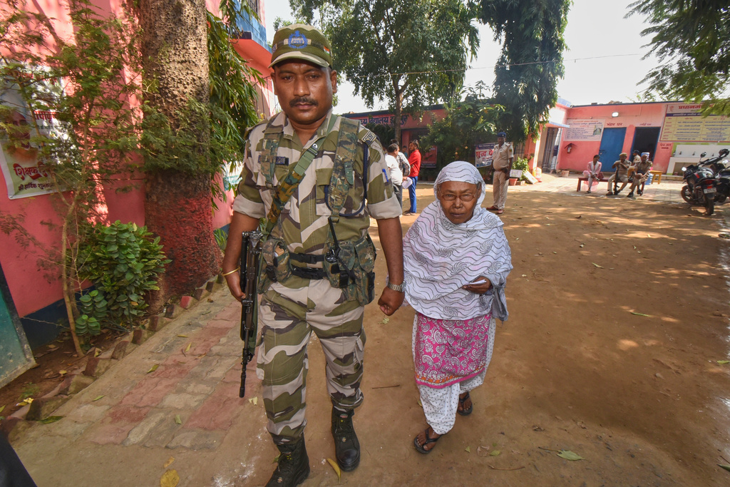 A para-military force soldier escorts an elderly woman to a polling booth to cast her vote during Bihar state election in Patna, India, Thursday, Nov. 6, 2025. (AP Photo)
