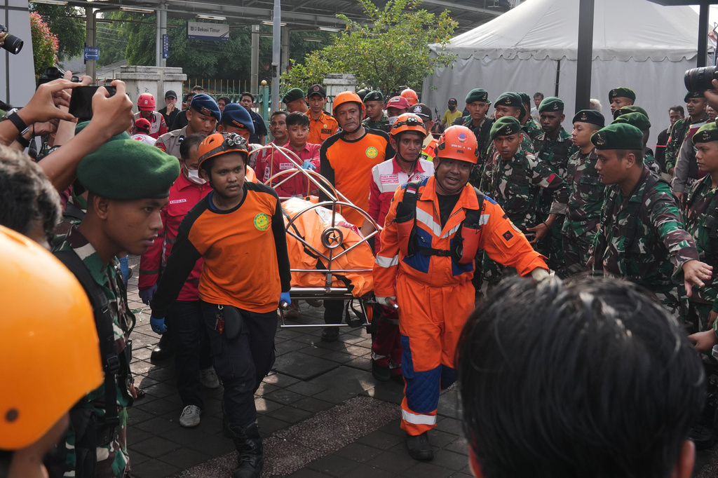 Rescuers carry the body of a victim of a train collision in Bekasi, Indonesia, Tuesday, April 28, 2026. (AP Photo/Tatan Syuflana)