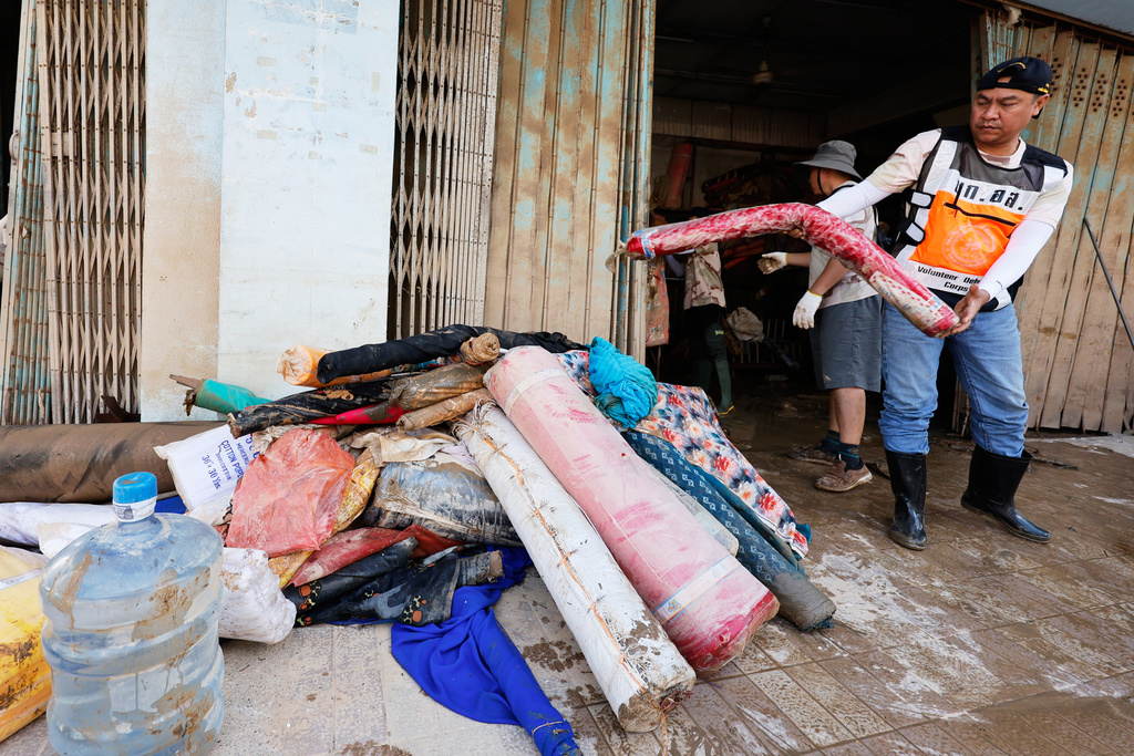 Volunteers move rolls of fabric damaged from floods in Songkhla province, southern Thailand, Sunday, Nov. 30, 2025. (AP Photo/Sarot Meksophawannakul)