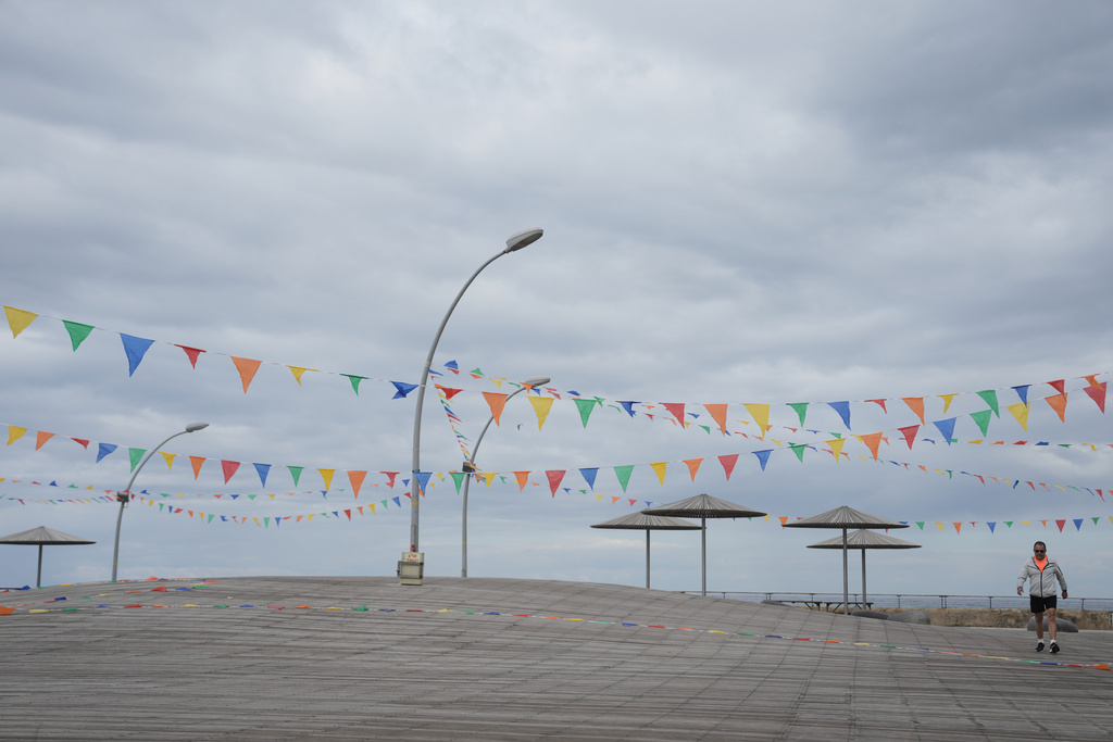 A man walks on empty boardwalk at the Tel Aviv port , Israel, after alarms announced that Israel had launched an attack on Iran, Saturday, Feb. 28, 2026. (AP Photo/Oded Balilty)