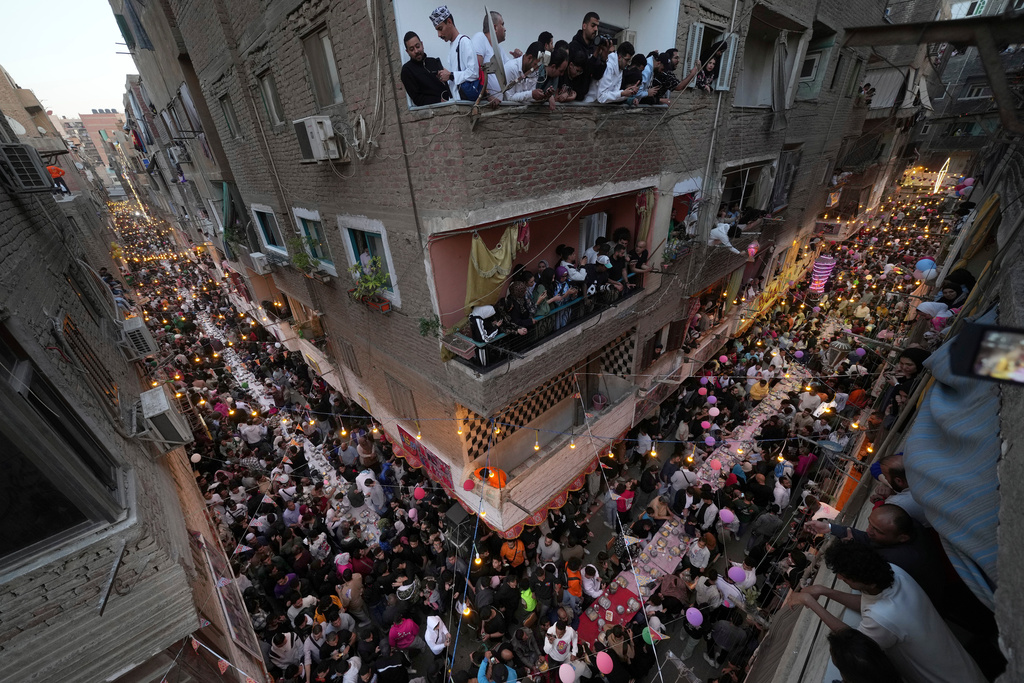 FILE - Residents of Ezbet Hamada in Cairo's El Matareya district peer from their balconies to celebrate a mass break-fast, "Iftar" during the holy fasting month of Ramadan in Cairo, March 15, 2025. (AP Photo/Amr Nabil, File)