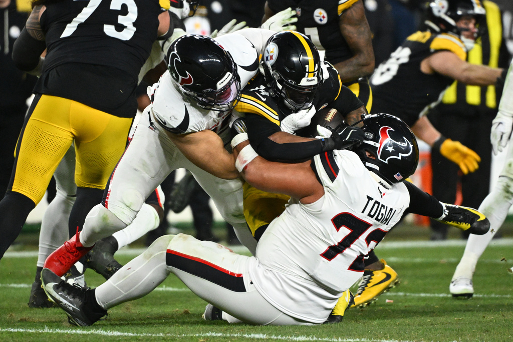 Pittsburgh Steelers running back Kenneth Gainwell is tackled by Houston Texans linebacker Henry To'oto'o, left, and defensive tackle Tommy Togiai (72) during the second half of an NFL wild-card playoff football game, Monday, Jan. 12, 2026, in Pittsburgh. (AP Photo/Justin Berl)