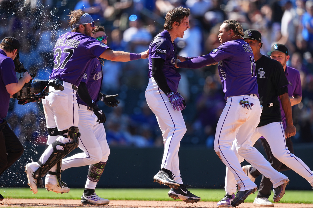 Colorado Rockies' Mickey Moniak, center, celebrates after his walkoff RBI single with Braxton Fulford (37) and Tyler Freeman, back left, and Orlando Arcia, front right, in the ninth inning of a baseball game against the Chicago Cubs, Sunday, Aug. 31, 2025, in Denver. (AP Photo/David Zalubowski)